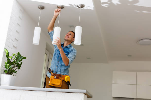 portrait of a male electrician fixing light on ceiling